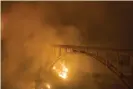  ?? Photograph: Nic Coury/AP ?? The Colorado fire burns below Rocky Creek bridge, one of two bridges engulfed in wildfire on Highway 1 near Big Sur, California.