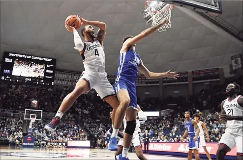  ?? Jessica Hill / Associated Press ?? UConn’s Tyrese Martin, left, is fouled by Central Connecticu­t State’s Arian Dehnavi on Tuesday in Storrs.