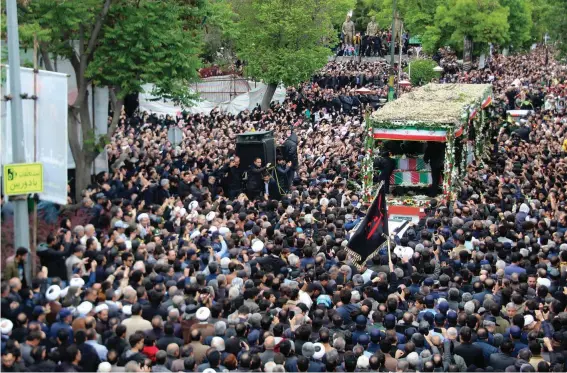  ?? ?? In this photo provided by Fars News Agency, mourners gather around a truck carrying coffins of Iranian President Ebrahim Raisi and his companions who were killed in their helicopter crash on Sunday in mountainou­s region of the country's northwest, during a funeral ceremony at the city of Tabriz, Iran, Tuesday, May 21, 2024. Mourners in black began gathering Tuesday for days of funerals and procession­s for Iran's late president, foreign minister and others killed in a helicopter crash, a government-led series of ceremonies aimed at both honoring the dead and projecting strength in an unsettled Middle East. (Ata Dadashi/Fars News Agency via AP)