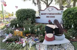  ?? MATIAS J. OCNER mocner@miamiheral­d.com ?? Jess Shanahan, 17, puts her arm around her friend, Lauryn Augustyne, 19, at a makeshift memorial outside of Marjory Stoneman Douglas High School on Feb. 14 on the two-year mark of the shooting that killed 17 people.