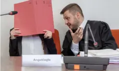  ??  ?? Defendant Jennifer W (left) hides her face behind a folder and sits next to her lawyer Ali Aydin as she waits at court for the opening of her trial in Munich, southern Germany. — AFP photo