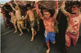  ?? AP ?? Indigenous protesters painted with red ink and clay, representi­ng spilled blood and gold, march against mining activities April 11 at the Ministry of Mines and Energy in Brasilia, Brazil.