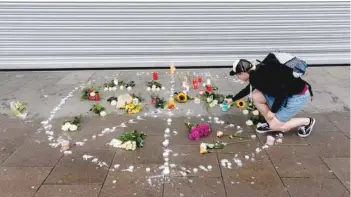  ?? — AFP ?? A woman places a candle at a makeshift memorial of flowers and candles arranged like a peace sign on Saturday in Hamburg, at the site where a man killed one person and wounded several others in a knife attack the day before.