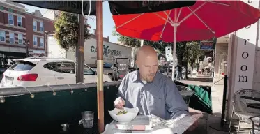  ?? GREG SOUTHAM/ EDMONTON JOURNAL ?? Jeff Gusdal enjoys a meal on Whyte Avenue. Most of the city’s outdoor patios are on major streets.