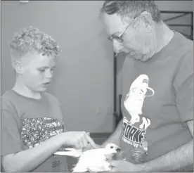  ?? Mona Weatherly ?? Leon Freeman, right, holds two racing pigeons while Brent Forster, 12, touches the feathers to feel the texture. Brent is the son of Helen and Adam Forster of Broken Bow.
