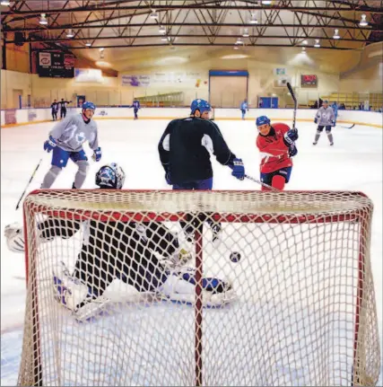  ?? RENE JOHNSTON/TORONTO STAR ?? Tie Domi, a vision in red, whips a shot past Eddie Belfour at the Centennial Centre in Gravenhurs­t, where the Maple Leafs are bonding.