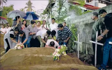  ?? Gemunu Amarasingh­e Associated Press ?? MOURNERS grieve after the burial of three members of one family who were killed at St. Sebastian Church in Negombo, Sri Lanka. The government blamed an obscure extremist group, National Thowheeth Jamaath.