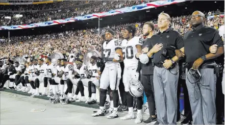  ?? Alex Brandon ?? The Associated Press Some members of the Oakland Raiders sit while others stand and link arms during the national anthem before their game Sunday against the Washington Redskins in Landover, Md.
