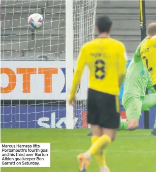  ??  ?? Marcus Harness lifts Portsmouth’s fourth goal and his third over Burton Albion goalkeeper Ben Garratt on Saturday.