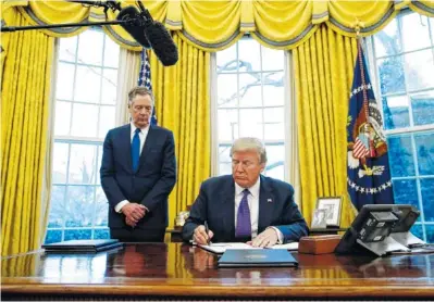  ?? THE ASSOCIATED PRESS ?? President Donald Trump, joined by U.S. Trade Representa­tive Robert Lighthizer, signs Section 201 actions in the Oval Office of the White House in Washington Tuesday. Trump says he is imposing new tariffs to "protect American jobs and American workers."