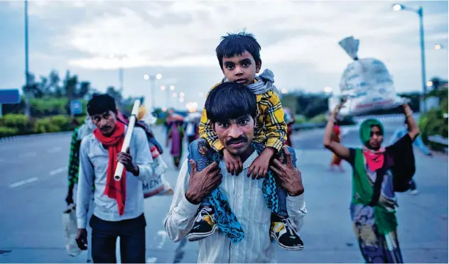  ?? Reuters ?? ↑
A migrant worker carries his son as they walk along a road in New Delhi on Thursday.