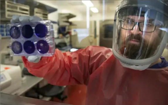  ?? Nate Guidry/Post-Gazette ?? Matt Dunn, a researcher for the Center for Vaccine Research at the University of Pittsburgh, holds dead samples of the new coronaviru­s Thursday at the Biomedical Science Tower 3 in Oakland. Visit post-gazette.com for a video report.