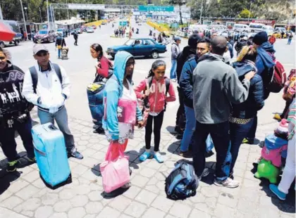  ?? AP ?? La venezolana Sandra Cadiz; su hija Angelis, de 10 años, y otros migrantes esperaban en el puesto fronterizo de Ipiales, Colombia, antes de seguir hacia Ecuador, por el puente internacio­nal Rumichaca (fondo).