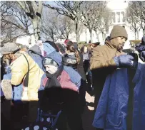  ?? File photo by Ernest A. Brown ?? In the shadow of the Rhode Island Statehouse, people look for warm coats, hats, mittens and scarves during the annual Buy Nothing Day Coat Exchange in Providence in 2018. The Buy Nothing Day Coat Exchange returns this year.