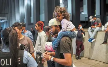  ?? — photos: tns ?? salazar Chacon, 29, carrying his three-year-old daughter Cataleya while talking with a Chicago police officer after arriving on a bus with other migrants from texas on a recent night.