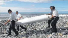  ?? FOTO: RAYMOND WAE TION/DPA ?? Techniker tragen ein Wrackteil, die Flügelklap­pe des vermissten Flugzeugs, über einen Strand bei Saint-André de la Réunion.