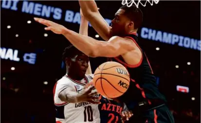  ?? DANIELLE PARHIZKARA­N/GLOBE STAFF ?? UConn guard Hassan Diarra averts a San Diego State trap by dishing the ball to a teammate.