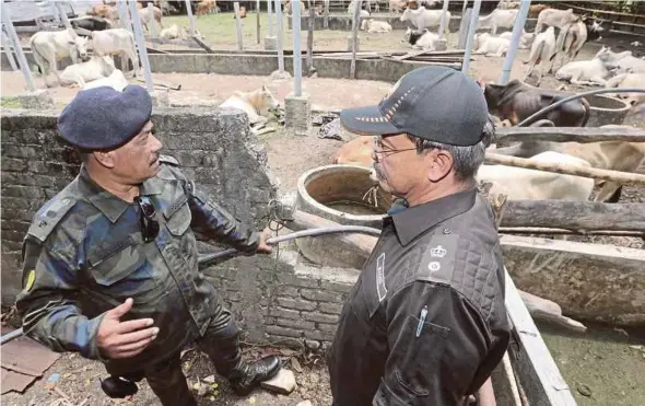  ?? PIC BY FATHIL ASRI ?? General Operations Force Ninth Battalion commanding officer Superinten­dent Ramly Poncho (left) handing over the seized livestock to the Kelantan Department of Malaysian Quarantine and Inspection Service for further action.