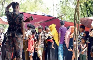  ?? AFP ?? A Bangladesh border guard watches Rohingya refugees at the Jalpatoli refugee camp in the noman’s land area between Myanmar and Bangladesh, near Gumdhum village on Saturday. —