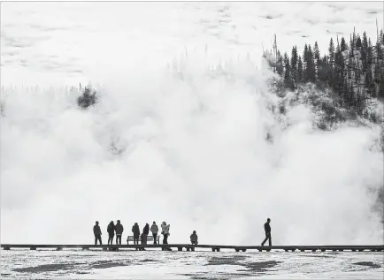  ?? JOSH HANER NYT ?? Visitors are shown at the Grand Prismatic Spring in Yellowston­e National Park on Oct. 15. Climate change is altering America's first national park so quickly that plants and animals may not be able to adapt.