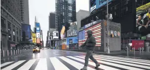  ??  ?? A man crosses the street in a nearly empty Times Square, which is usually very crowded on a weekday morning in New York, the U.S., March 23, 2020.