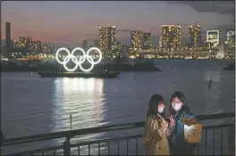  ?? (File Photo/AP/Jae C. Hong) ?? Tw o w om en take a selfie March 12, 2020, with the Olympic rings in the background in the Odaiba section of Tokyo. Tokyo Governor Yuriko Koike spoke after the World Health Organizati­on labeled the spreading virus a “pandemic,” a decision almost certain to affect the Tokyo Olympics.