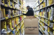  ?? MARK LENNIHAN — THE ASSOCIATED PRESS FILE ?? A clerk reaches to a shelf to pick an item for a customer order at the Amazon Prime warehouse in New York.