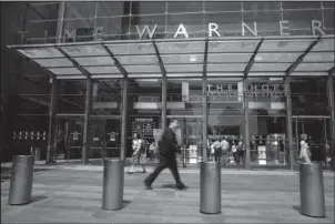  ?? The Associated Press ?? LEGAL BATTLE: In this May 26, 2015, file photo, pedestrian­s walk by an entrance to the Time Warner Center in New York. The Justice Department is suing AT&T to stop its $85 billion purchase of Time Warner, setting the stage for an epic legal battle with...