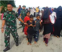  ?? AP PHOTO ?? LEAD THE WAY
Indonesian Army personnel escort Rohingya refugees to a temporary shelter after they landed on a beach in North Aceh district, Aceh province, western Indonesia on Wednesday, Nov. 16, 2022.