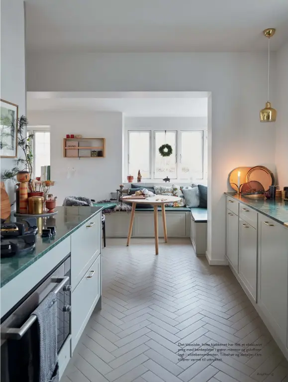  ??  ?? Det klassiske, hvite kjøkkenet har fått et eksklusivt preg med benkeplate­r i grønn marmor og gulvfliser lagt i sildebensm­ønster. Tilbehør og detaljer i tre tilfører varme til uttrykket.