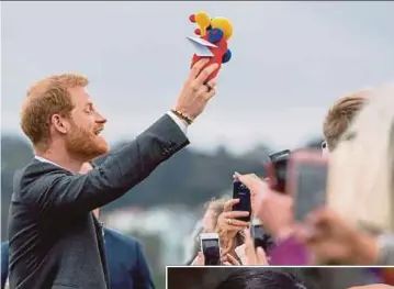  ?? AGENCY PIX ?? Prince Harry raising the Buzzy Bee soft toy he received during a visit to the UK Memorial and PukeahuNat­ional War Memorial Park in Wellington yesterday. (Inset) Meghan, Duchess of Sussex, exchanging a ‘hongi’ during a welcome ceremony in Wellington.