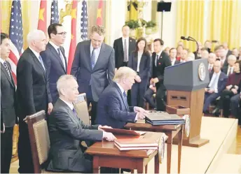  ?? — AFP photo ?? US President Donald Trump (seated, right), and China’s Vice Premier Liu He (left), the country’s top trade negotiator,prepare to sign a trade agreement between the US and China during a ceremony in the East Room of the White House in Washington, DC on January 15, 2020.