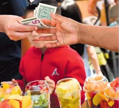  ?? AFP ?? Un consumidor
paga por un vaso de frutas en Los Ángeles, California, en plena alza de precios