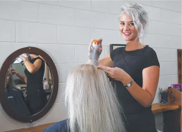  ?? Picture: BRENDAN RADKE ?? CAN-DO ATTITUDE: Zeal Hair salon apprentice Kianna Darcey applies dry shampoo to a client’s hair.
