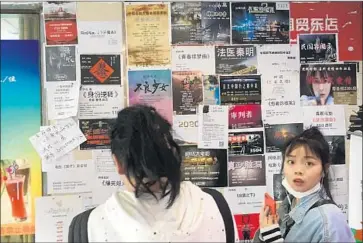  ?? Photograph­s by Matt DeButts For The Times ?? AGENT Zhong Xu, left, examines fliers seeking actors in the lobby of the Floating Home hotel. Many of the fliers are out of date. “Three to five new studios still arrive per week,” he said. “It’s still worth coming here.”