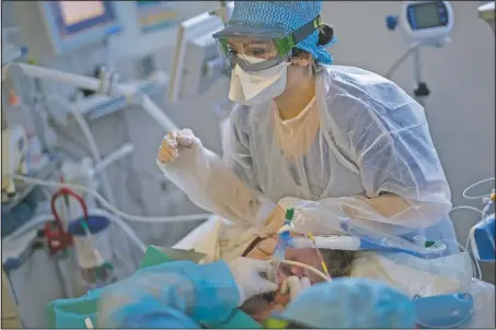  ??  ?? Nurses clean and adjust an endotrache­al tube providing respirator­y assistance to a 61-year-old covid-19 patient in the ICU.