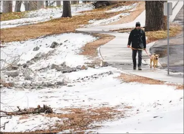  ?? Myung J. Chun Los Angeles Times ?? KEVIN WOODS takes a morning walk with Sadie in Frazier Park on Wednesday after an overnight storm brought snow to the area. The storm isn’t likely to make much of an impact on California’s critically dry year.