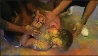  ?? ?? People put colored powder on their friend to celebrate Holi on Tuesday in Prayagraj, India.