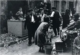  ??  ?? Foto d’una parada ambulant del barri xino.
Un nen passejant amb el seu gos en braços al carrer Arc del Teatre.
Michaelis fotografia els edificis, però també mira els qui hi viuen.