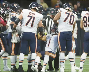  ?? JOHN J. KIM / CHICAGO TRIBUNE ?? Teammates help Bears quarterbac­k Justin Fields (1) to his feet after he was tackled during the final offensive drive late in the fourth quarter at Mercedes-Benz Stadium on Sunday. Fields was injured on the play.