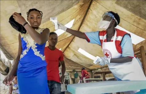  ?? Ronald Kabuubi/Associated PRess ?? People coming from Congo on Friday have their temperatur­e measured to screen for symptoms of Ebola, at the Mpondwe border crossing with Congo, in western Uganda. In Uganda, health workers had long prepared in case the Ebola virus got past the screening conducted at border posts with Congo. It did earlier this week, when a family exposed to Ebola while visiting Congo returned home on an unguarded footpath.