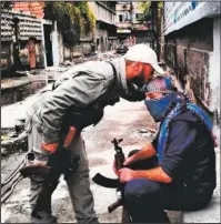  ?? Submitted photo ?? BROTHERS IN ARMS: A soldier in the Free Syrian Army comforts another on a street in Syria.