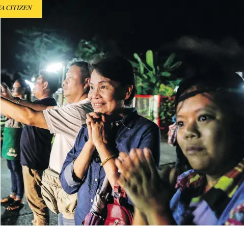  ?? LAUREN DECICCA / GETTY IMAGES ?? Onlookers watch and cheer as ambulances deliver boys rescued from a cave in northern Thailand to hospital in Chiang Rai on Sunday. Divers began a rescue operation to pull the 12 boys and their soccer coach out of the flooded cave early Sunday.