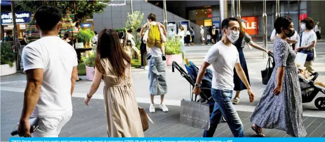  ?? — AFP ?? TOKYO: People wearing face masks amid concerns over the spread of coronaviru­s (COVID-19) walk at Futako Tamagawa neighborho­od in Tokyo yesterday.