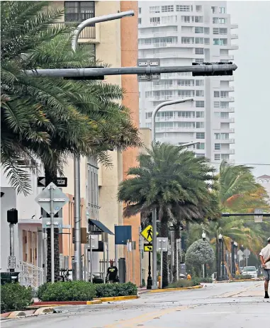  ??  ?? Above left, the projected path of Hurricanes Irma and Jose; above, a deserted Miami Beach after millions evacuate; left, a woman and child use a blanket as protection from wind and rain on the Cuban island of Caibarién