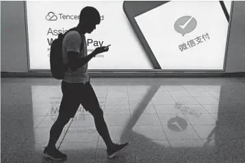  ?? RICHARD A. BROOKS/GETTY-AFP 2017 ?? A man walks past an advertisem­ent for the WeChat social media platform at Hong Kong’s internatio­nal airport.