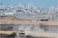  ?? LEO CORREA THE ASSOCIATED PRESS ?? Israeli soldiers move on the top of a tank near the Israeli-Gaza border as seen from southern Israel on Tuesday.