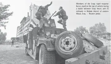  ??  ?? Members of the Iraqi rapid response forces stand on the top of vehicle during a battle between Iraqi forces and IS militants in Wahda district of eastern Mosul, Iraq. — Reuters photo