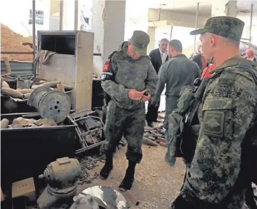  ??  ?? Fuerzas rusas inspeccion­an material militar de la insurgenci­a abandonado en Duma