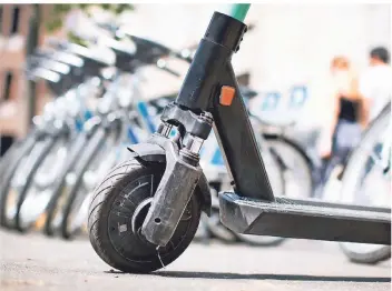  ?? FOTO: MARTIN GERTEN/DPA ?? Ein E-scooter und Fahrräder zum Ausleihen stehen in der Innenstadt. Einen Überblick über buchbare Verkehrsmi­ttel aller Art bieten neue Apps.